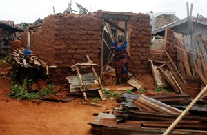 A woman stands helplessly beside her roofless home after a rainstorm in Lagos