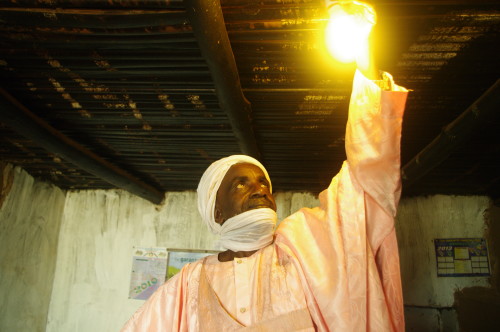 Ardo Abdou Karimu admires light from solar power at his   home in Kingomen village. Photo credit: Arison TAMFU