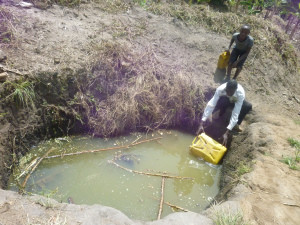 A man and his son fetching water from a shallow well in Kakiika, Mbarara district of Uganda
