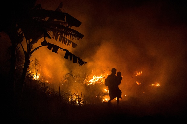A man carries his son through the haze on the way to his house as fires burn peatland and fields at Ogan Ilir in Palembang. Photo credit: Ulet Ifansasti/Getty Images