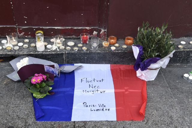 Flowers, candles and the French national flag with the Latin, "Tossed but not sunk" the motto of Paris written on it, is laid outside of the Carillon, adjacent to the Cambodian restaurant on Rue Alibert in the 10th district, of the French capital Paris, on November 14, 2015, the morning after an attack which killed 12 people at the restaurant. Islamic State jihadists claimed a series of coordinated attacks by suicide bombers and gunmen in the city that killed at least 128 people at a concert hall, restaurants and the national sports stadium. Photo credit: AFP/Dominique Faget/Getty Images