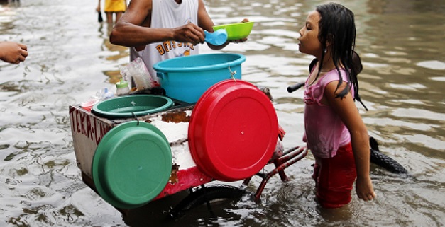 A young Filipino buys food from a vendor on a flooded street in Malabon, north of Manila, Philippines, 08 July 2015. According to the Philippines State weather forecast, heavy rainfall is expected in Metro Manila and nearby provinces due to an enhanced Southwest Monsoon and Tropical Storm Linfa, Typhoon Chan-hom and Typhoon Nangka which are lining up across the Pacific Ocean. Photo credit: EPA/FRANCIS R MALASIG