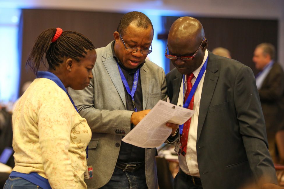 Dr I. A. Goji (right), Mr Leslie Adogame of SRADev Nigeria (middle) and an African delegate review the Earth Negotiations Bulletin (ENB) preparatory to discuss proceedings