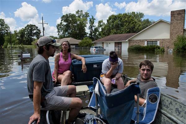 John Booth (left) sits with Angela Latiolais's family while helping them save belongings after flooding on Tuesday in Gonzales, Louisiana. Photo credit: Brendan Smialowski / AFP / Getty Images